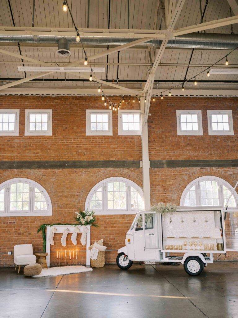 A small mobile bar truck with beer taps and a fireplace set up with holiday stockings inside of BRICK, a holiday party venue in San Diego, California. 