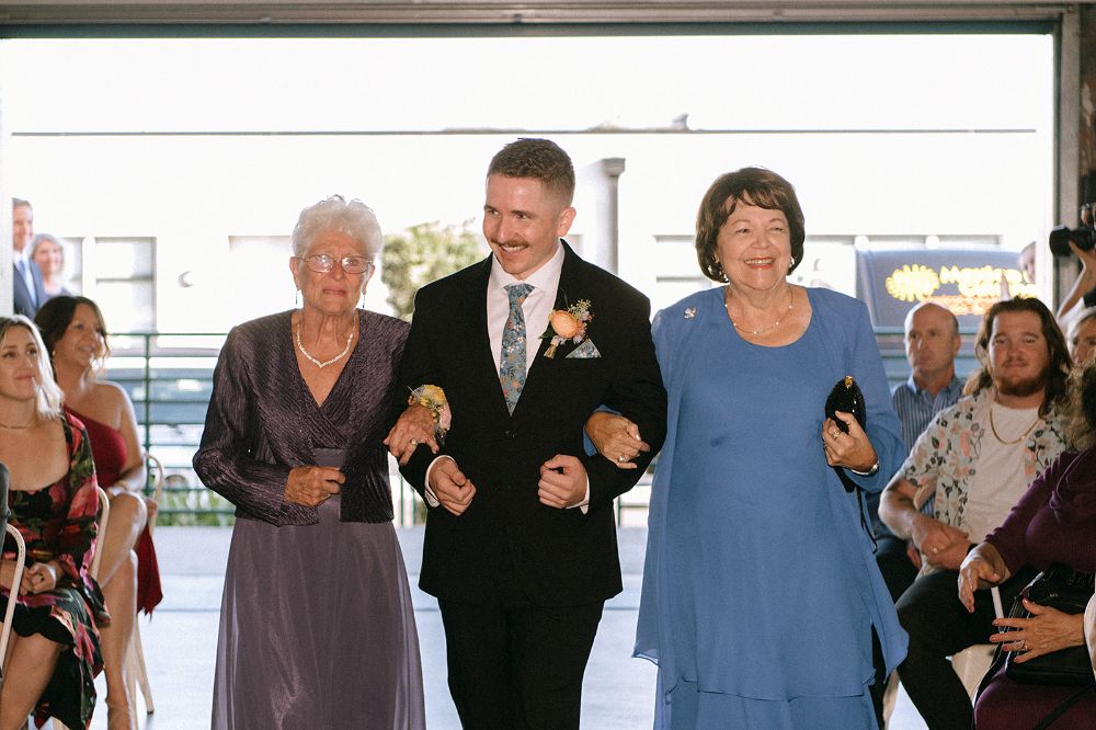 Groom walking down the aisle with mom and grandma