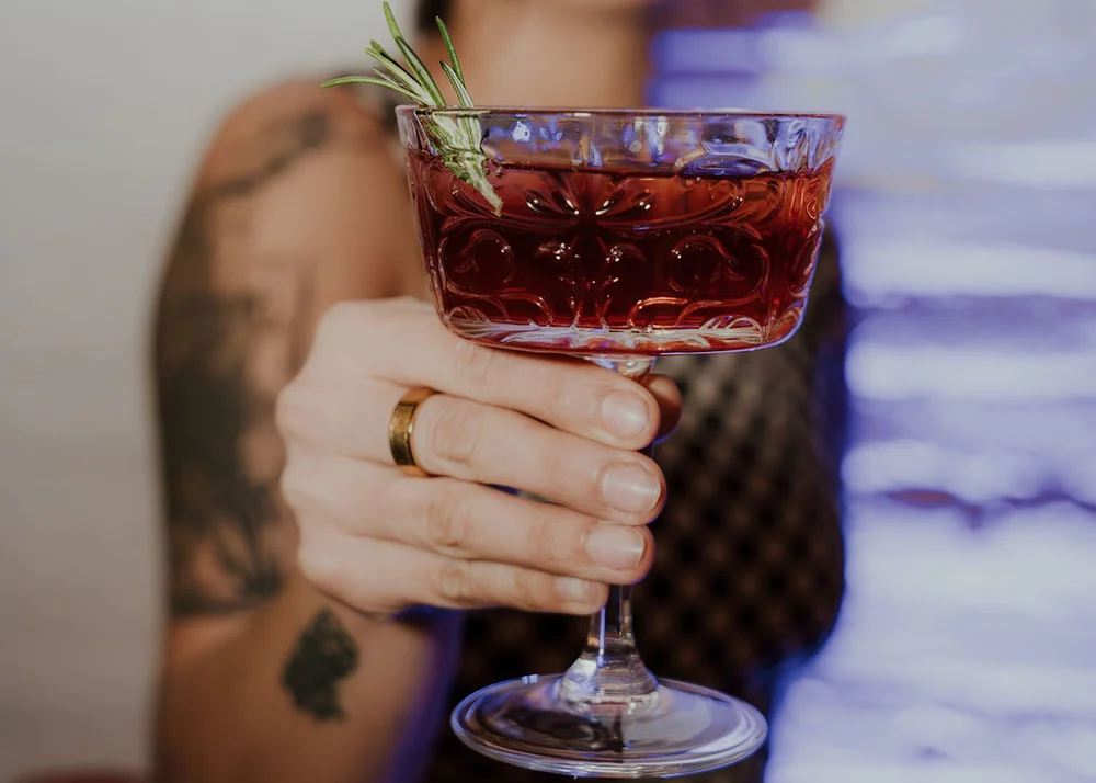 Red holiday cocktail with mint garnish in a vintage glass