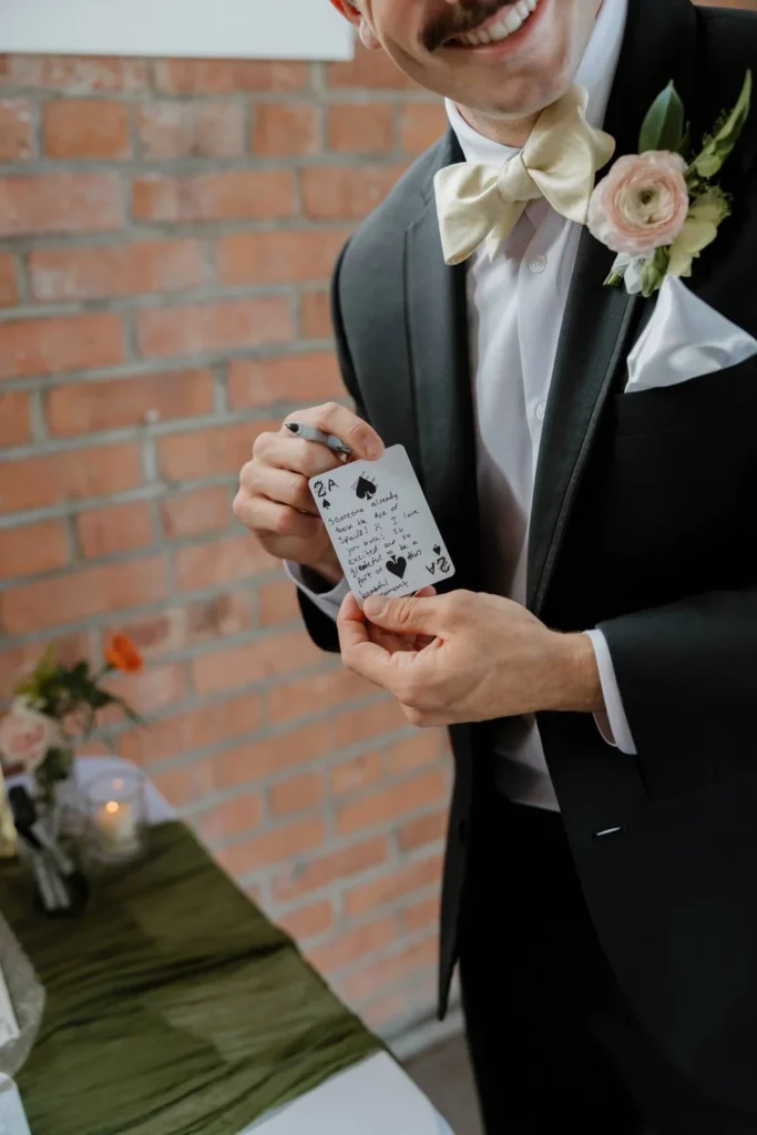 Wedding guest holding a playing card that he wrote a personal message on for the bride and groom at San Diego wedding at BRICK.