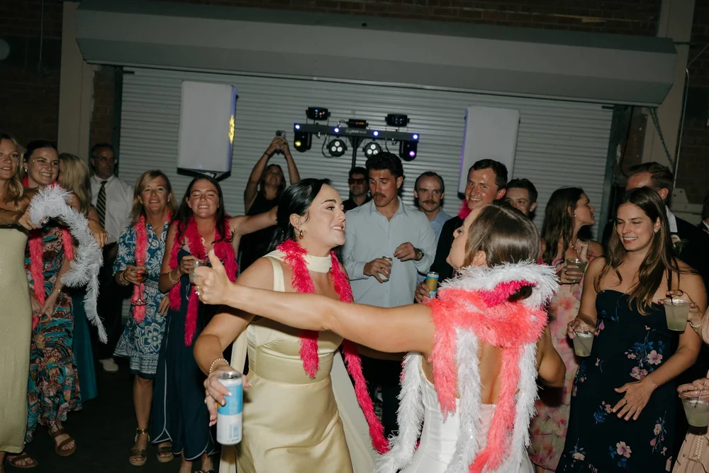 Guests dancing at a wedding reception at BRICK San Diego and wearing colorful boas.