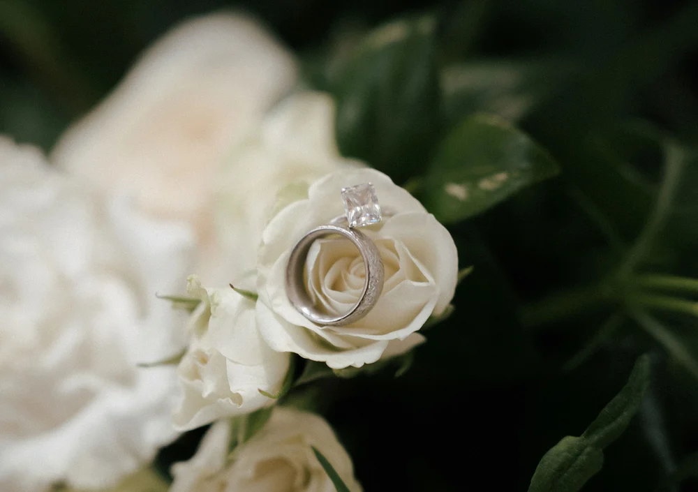 Wedding rings resting on a white rose, romantic detail for a San Diego wedding celebration
